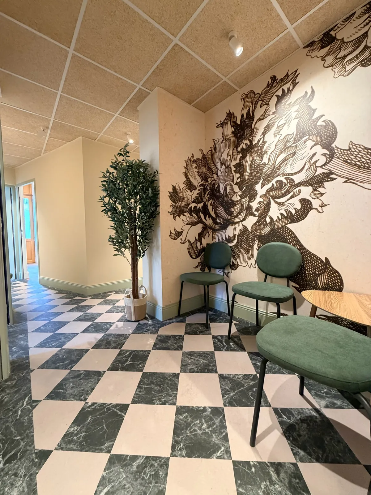 Espace d’attente des Chartrons : chaises vertes, décor floral et sol en damier